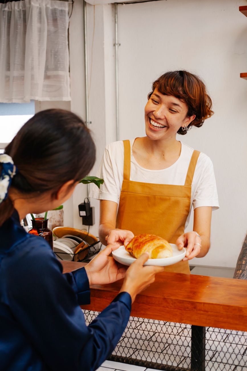 Baker in an apron serving fresh pastries in a bakery